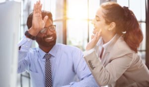 Uomo e donna in ufficio che si danno il cinque. Empatia in ambiente lavorativo.